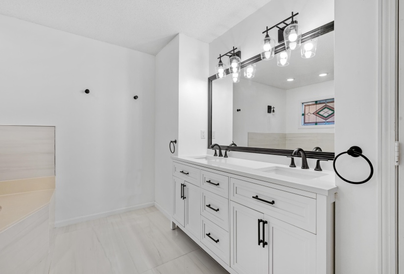 Dual vanity featuring white cabinetry, integrated sinks, and matte black hardware