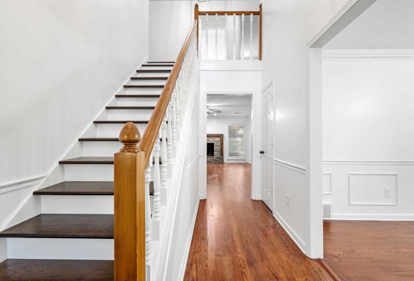 Grand foyer featuring rich wood-finish flooring and a staircase with white risers and dark treads