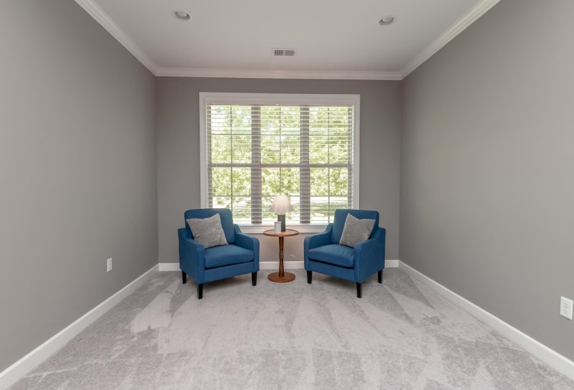 Bright room featuring a large window with blinds, recessed lighting, crown molding, and carpeted flooring
