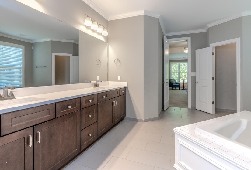 Dual vanity with white countertop and integrated sinks, dark wood-finish cabinetry, and chrome fixtures