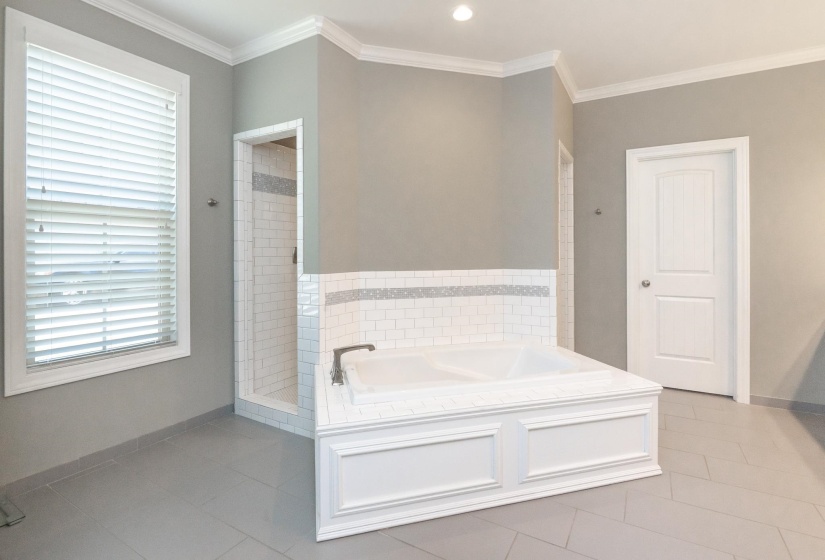 Soaking tub with white paneled surround and subway tile detailing