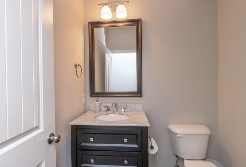 Bathroom featuring a dark wood vanity with a light-colored countertop, an undermount sink, and a framed mirror with a two-light fixture