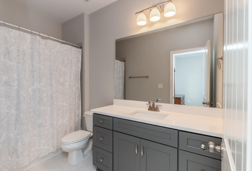 Vanity with gray shaker-style cabinetry, white countertop, and integrated sink