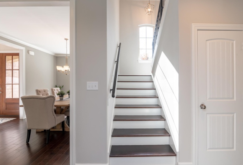 Staircase featuring dark wood-finish treads, white risers, and a black wrought iron handrail