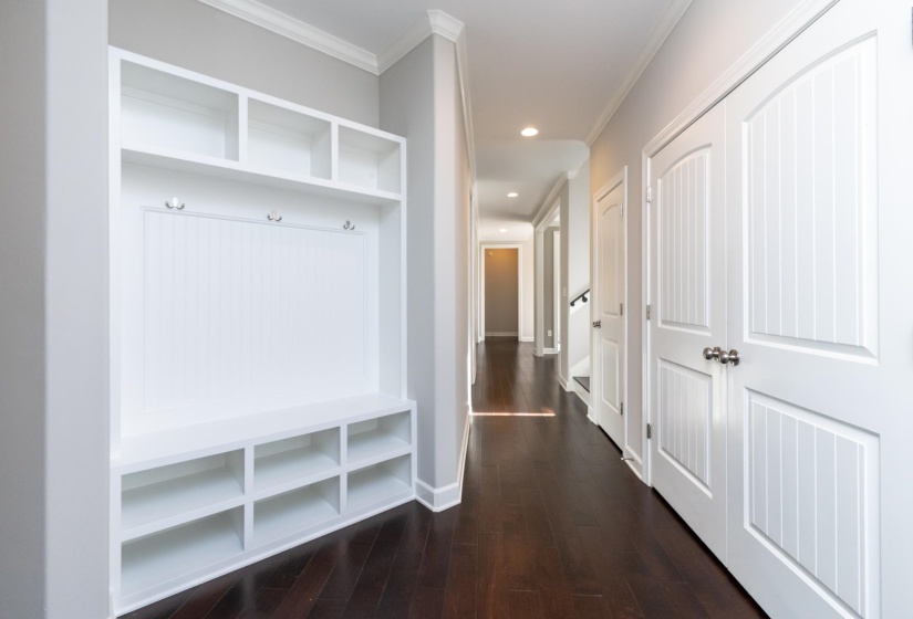 Built-in mudroom bench with cubbies and upper shelving, complemented by rich dark wood-finish flooring