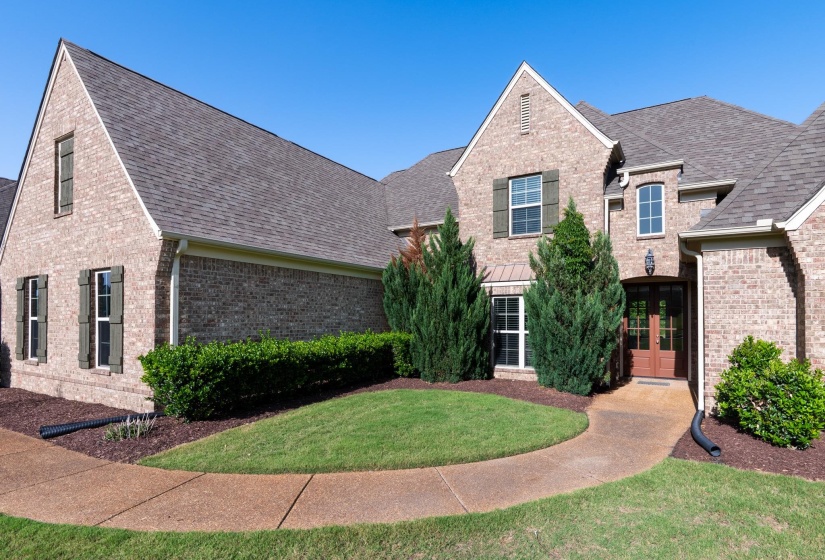 Traditional brick exterior with gabled rooflines, dark green shutters, and a prominent arched entryway
