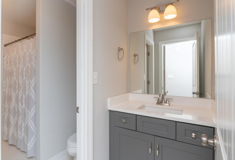 Bathroom vanity featuring a quartz countertop with an integrated sink, brushed nickel faucet, and a large wall-mounted mirror