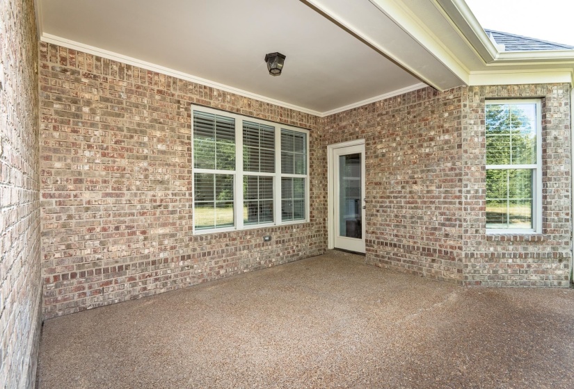 Covered patio featuring a durable aggregate surface, full brick exterior, crown molding, and recessed lighting