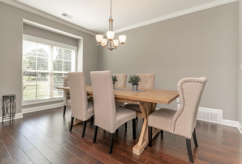 Dining area featuring wood-finish flooring, a recessed window, crown molding, and a five-light chandelier