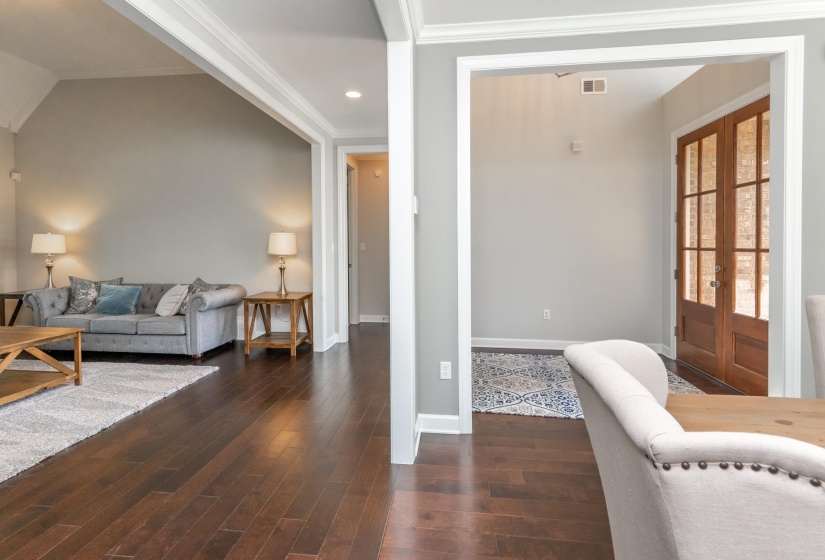 Open concept living area with wood-finish flooring, crisp white trim, and recessed lighting
