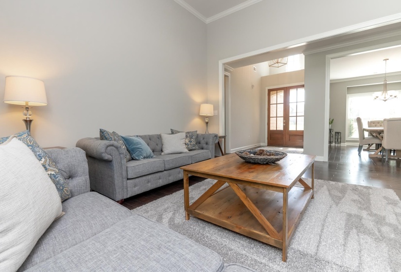Spacious living area featuring high ceilings, dark wood-finish flooring, and an expansive archway opening to the entryway