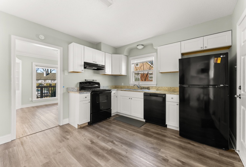 Kitchen featuring black appliances, white cabinets, dark wood-style floors, and light stone counters