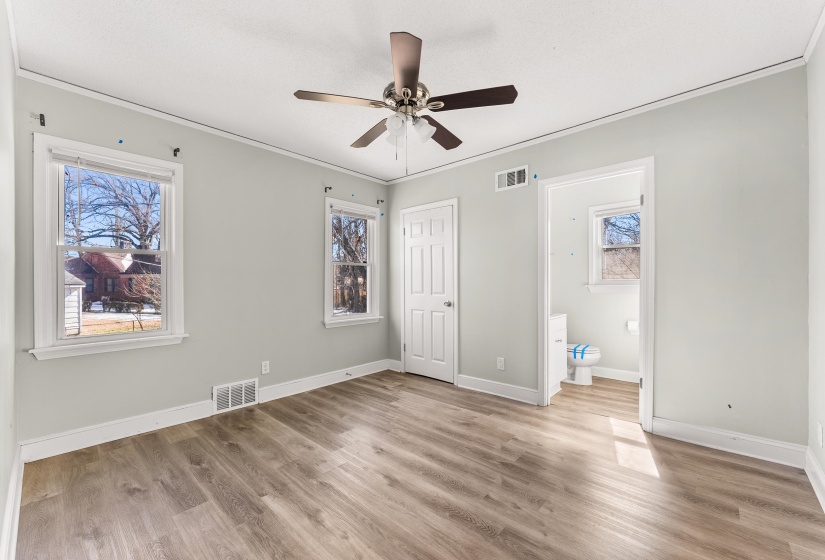 Unfurnished bedroom featuring light wood-type flooring, a ceiling fan, ornamental molding, and ensuite bath