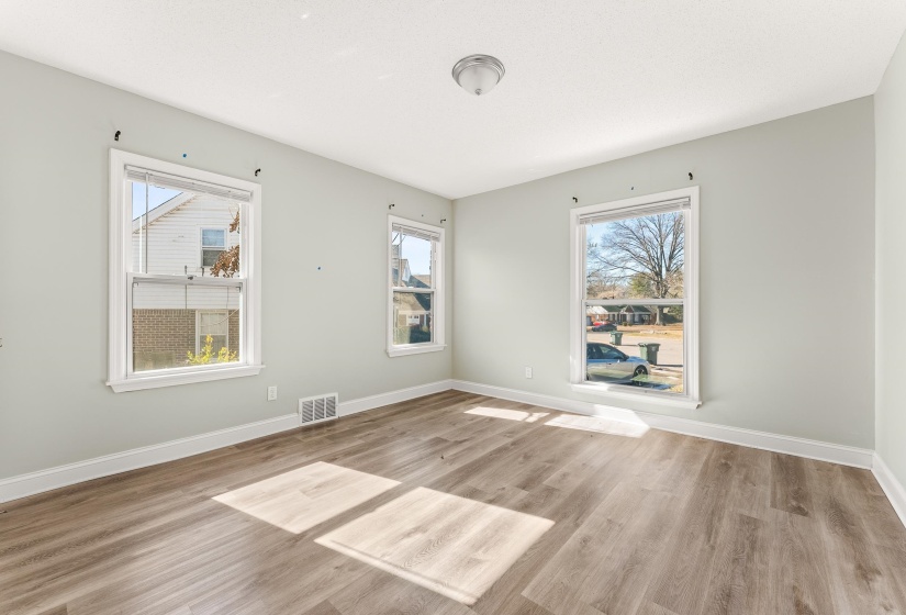 Empty room with light wood finished floors and healthy amount of natural light