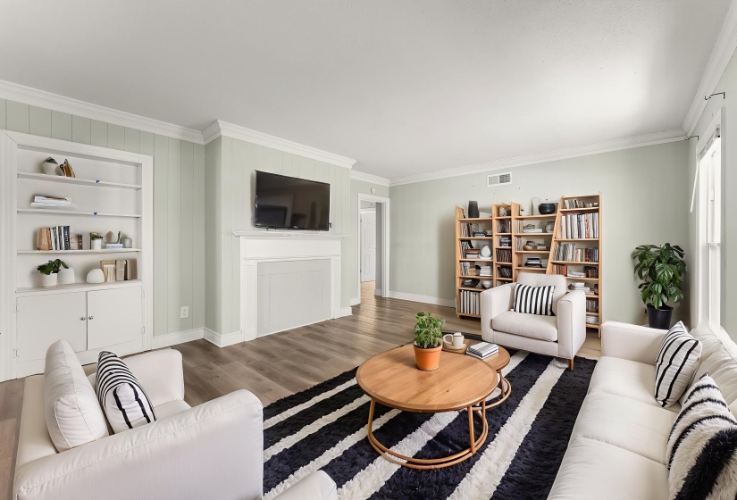 Living area with crown molding, built in features, and wood finished floors