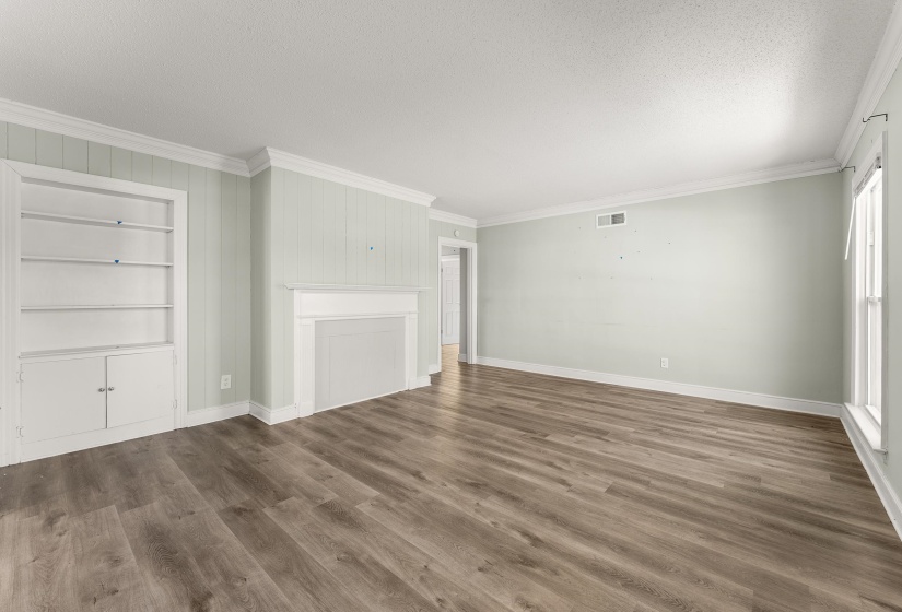 Unfurnished living room with ornamental molding, built in features, a textured ceiling, and dark wood finished floors