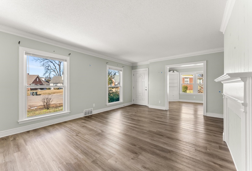 Unfurnished living room featuring ornamental molding, wood finished floors, and a textured ceiling