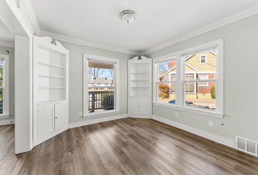 Unfurnished dining area featuring built in shelves, plenty of natural light, dark wood-style floors, and crown molding