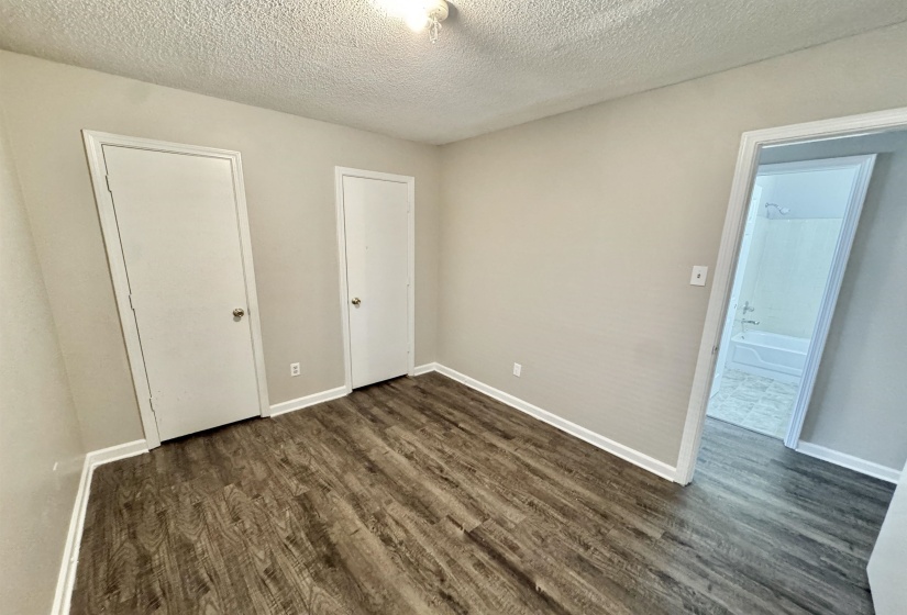 Interior room with wood-finish flooring, light neutral wall paint, and white baseboards