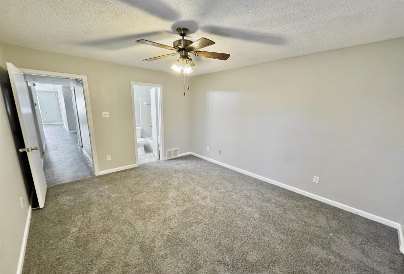 Carpeted room with a ceiling fan featuring a light fixture, light gray walls, and white baseboards