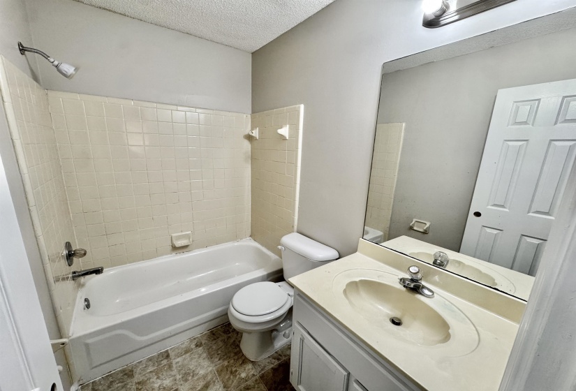 Full bathroom with a white tub-shower combination and tiled surround