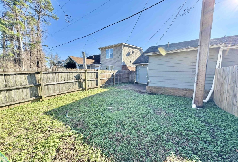 Fenced backyard featuring a gravel patio area and a detached structure with siding