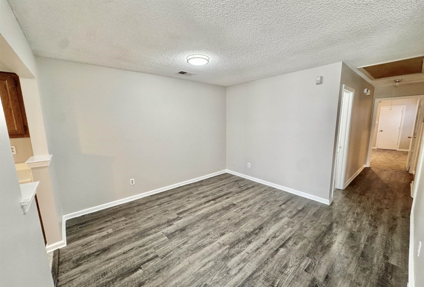 Spacious interior room featuring wood-finish flooring, white baseboards, and a contemporary flush-mount ceiling light