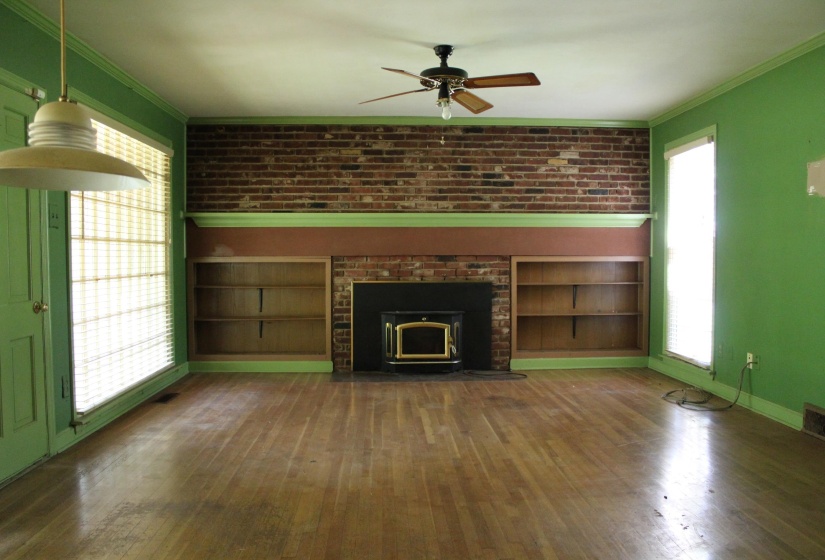 Interior room featuring wood-finish flooring and a brick-faced fireplace with an insert