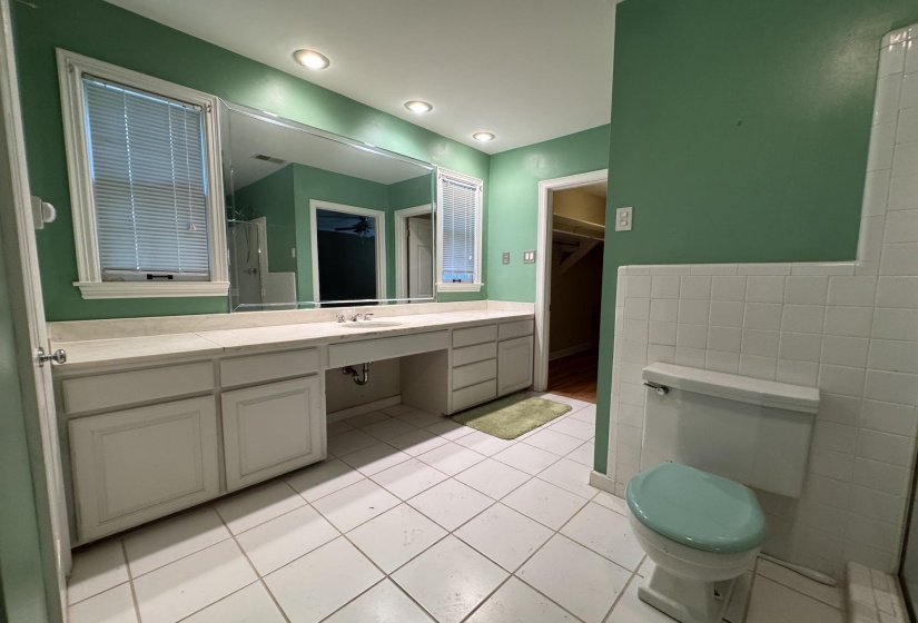Bathroom featuring an extended vanity with dual windows, integrated sink, and ample storage cabinetry