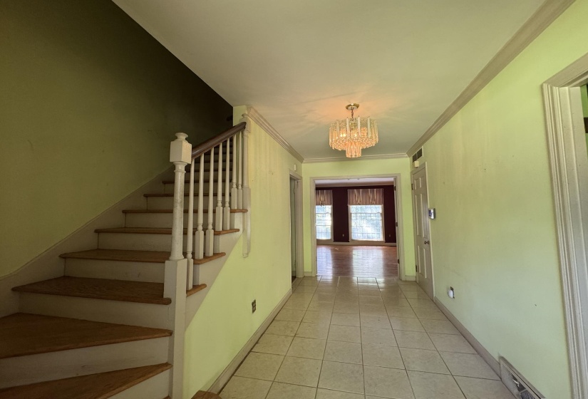 Entryway featuring a crystal chandelier, tiled flooring, and a staircase with wood-finish treads and white balusters