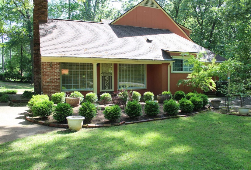 Front exterior featuring a brick chimney, a covered porch with column supports, and a terracotta-toned facade