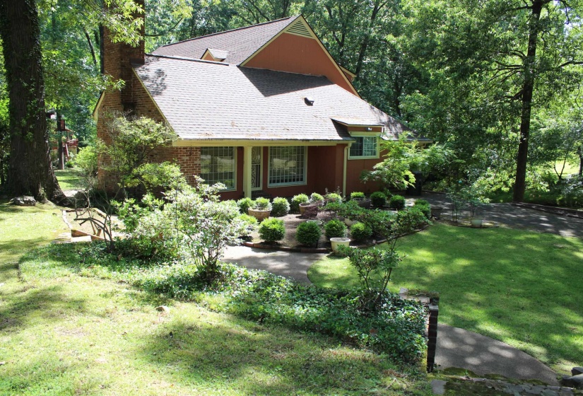 Exterior brick and stucco architecture featuring a shingled roof and a prominent brick chimney