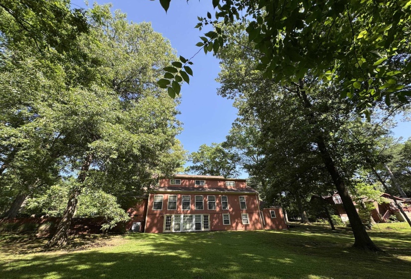 Rear exterior featuring a red brick facade, multiple levels of windows, two sets of white double doors, and a dormer window