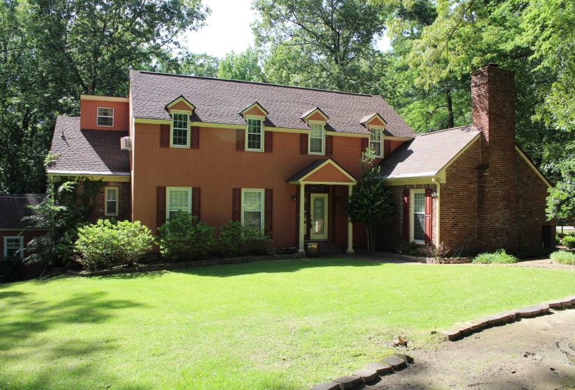 Two-story traditional residence featuring a brick chimney, dormer windows, and a covered entry