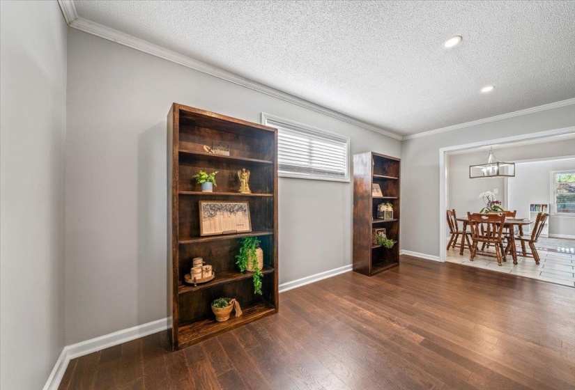 Hardwood flooring extending throughout the room, crown molding, recessed lighting, and a window with blinds