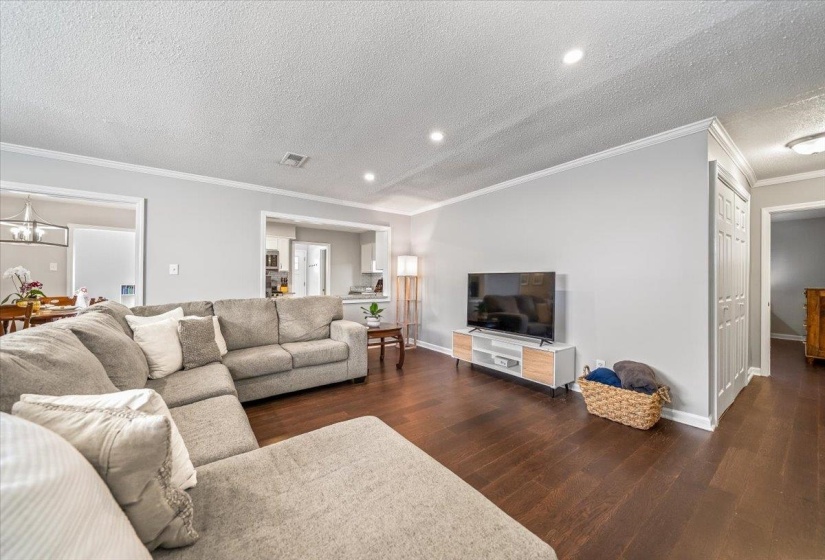 Open-concept living area featuring rich wood-finish flooring, light gray walls, and recessed ceiling lighting