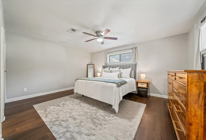 Spacious room featuring wood-finish flooring, a ceiling fan with integrated lighting, and neutral wall tones