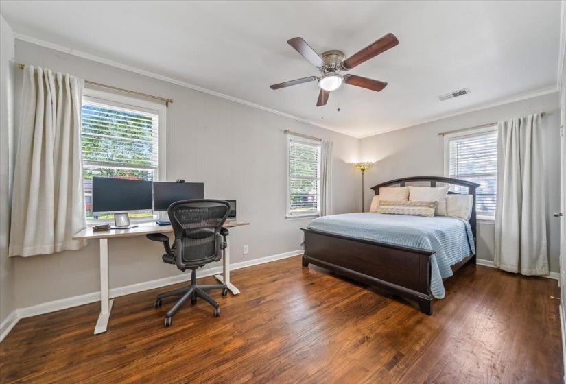 Bedroom featuring wood-finish flooring, white trim, and a ceiling fan with integrated lighting