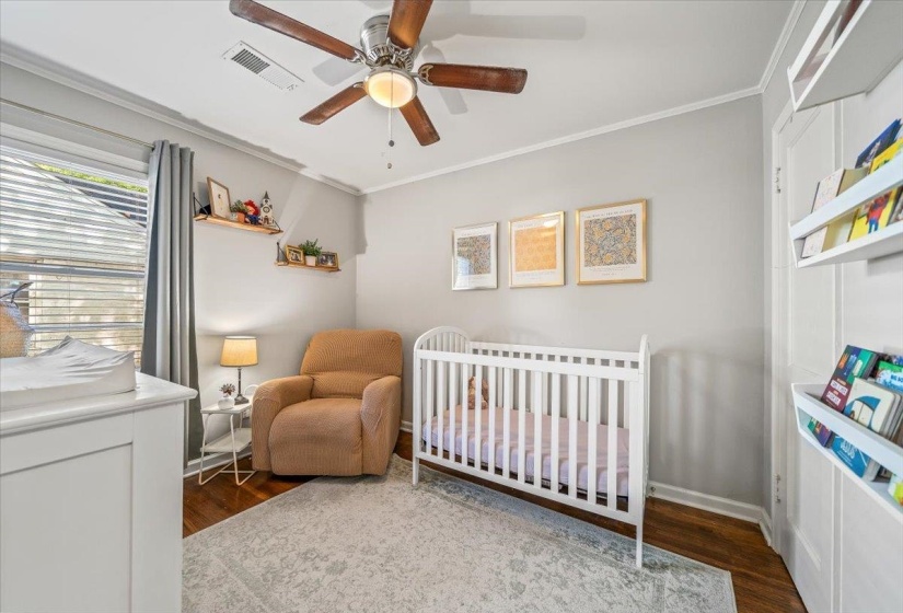 Hardwood flooring complements light gray walls in this room featuring crown molding, a ceiling fan, and a window with blinds