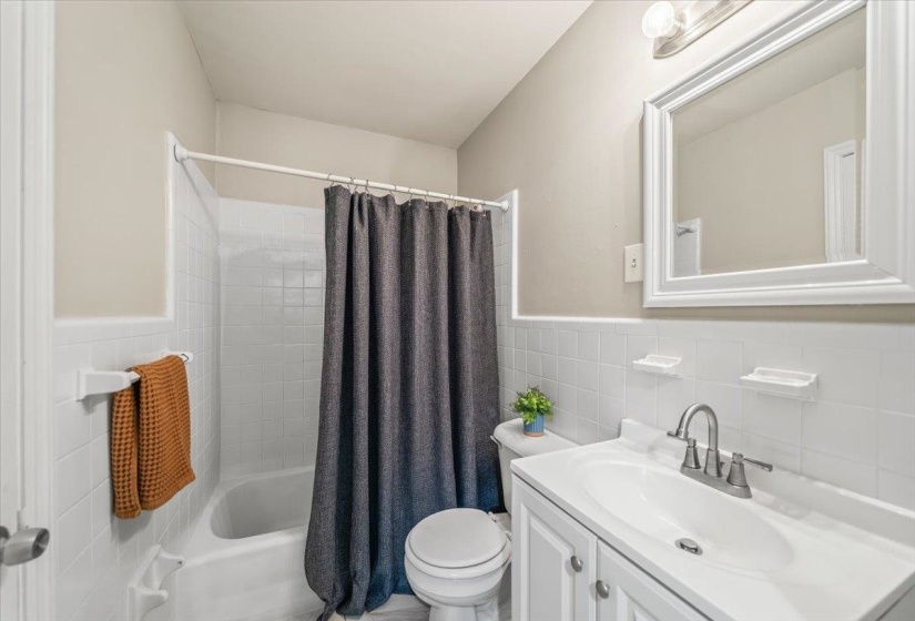 Bathroom featuring a white vanity with integrated sink, brushed nickel faucet, and a framed mirror