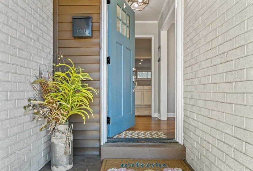 Entryway featuring a light blue front door, white brick facade, and horizontal wood-finish siding