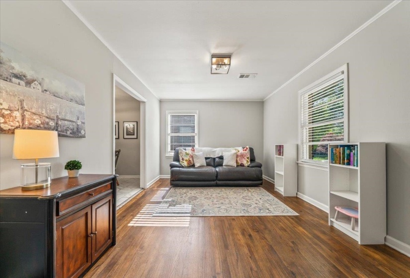 Spacious interior room featuring wood-finish flooring, light gray wall paint, and white trim