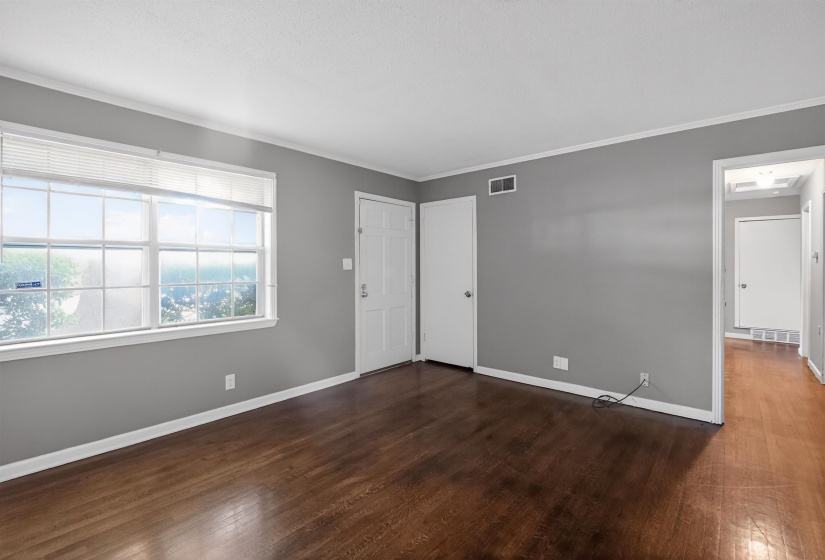 Spacious room featuring wood-finish flooring, light grey walls, and white trim