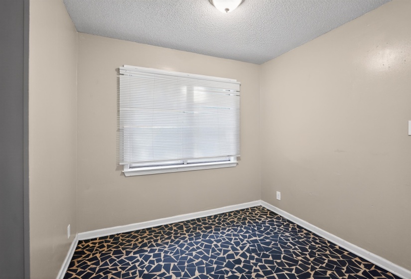 Room featuring neutral wall tones, a single window with blinds, and a ceiling-mounted light fixture