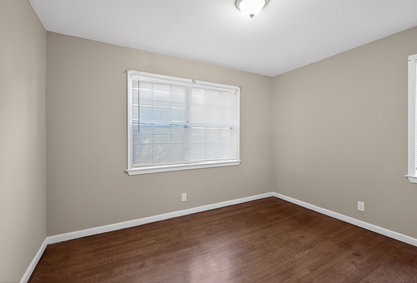 Room featuring wood-finish flooring, neutral wall paint, and white trim