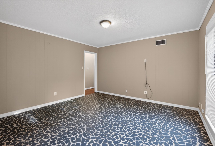 Spacious room featuring mosaic-patterned flooring, neutral wall tones, white trim, and a ceiling-mounted light fixture