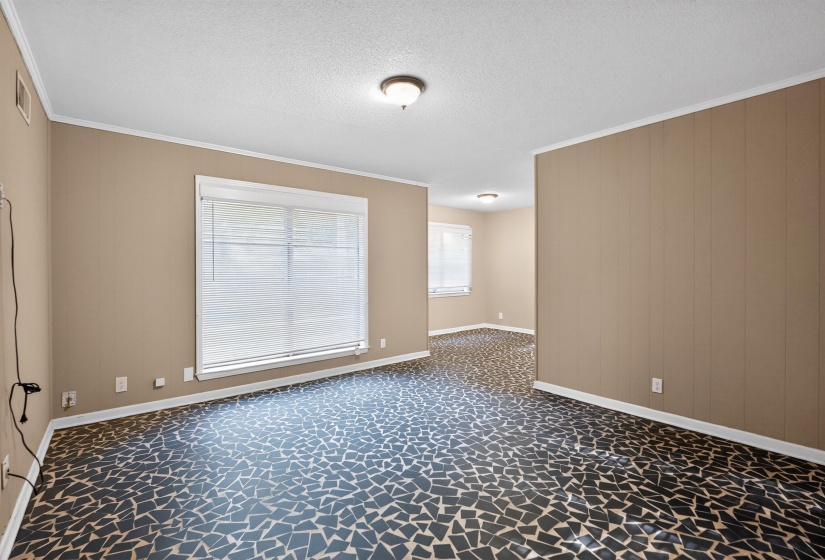 Spacious room featuring mosaic-patterned flooring, neutral-toned walls, and a large window with blinds