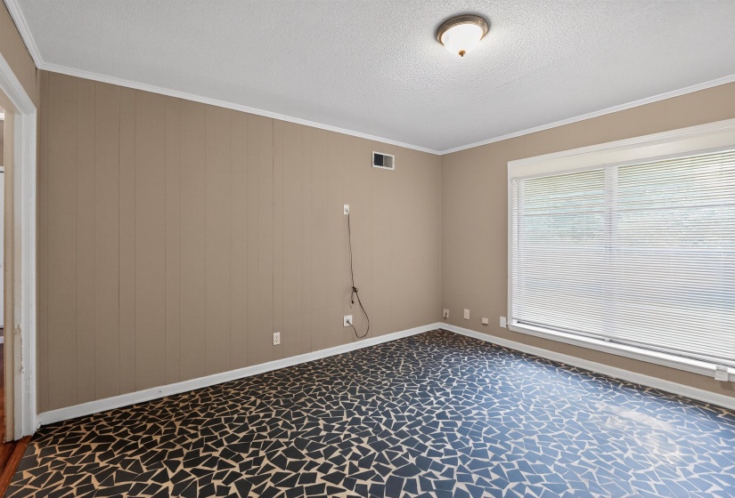 Spacious room featuring unique mosaic-style flooring, a large window with horizontal blinds, and paneled accent walls