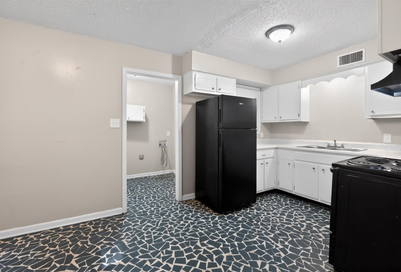Kitchen featuring white cabinetry, solid surface countertops, and a black appliance suite including a refrigerator and range
