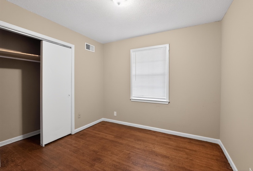 Room featuring wood-finish flooring, neutral wall tones, and white trim
